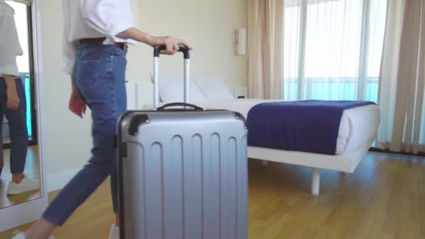 一位年轻性感的金发游客提着装有轮子的手提箱走进公寓 走近床 躺在床上或跌倒 享受生活 旅行和娱乐的概念 旅馆业 — 图库视频影像