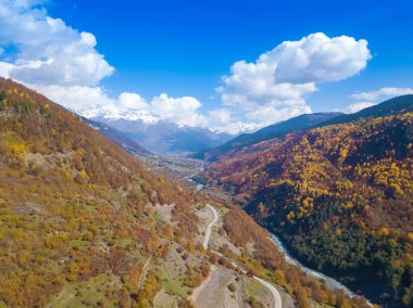 Güneşli bir sonbahar gününde dağların, yılanın, nehrin ve kırsal alanın uzaktan görüntüsü. İnsansız hava aracından Georgia 'nın Svaneti kentine güzel bir sonbahar manzarası