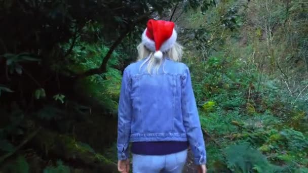 Camera Follows Young Blonde Santa Claus Hat Curved Tree Background — Video