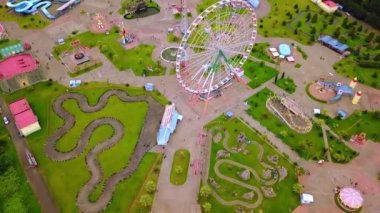 Top view of amusement park with Ferris wheel and roller coaster at sunset in Georgia at Tsitsinatela Park. Ferris wheel with air illumination. Recreation area of Georgian park on Black Sea coast.