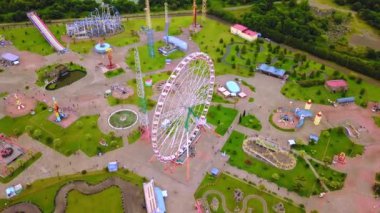 Top view of amusement park with Ferris wheel and roller coaster at sunset in Georgia at Tsitsinatela Park. Ferris wheel with air illumination. Recreation area of Georgian park on Black Sea coast.