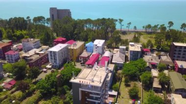Drone view of town of Kobuleti on Black Sea coast on sunny spring day, Georgia. Black Sea resort town with vacationers on sunny summer day with green spaces and trees.