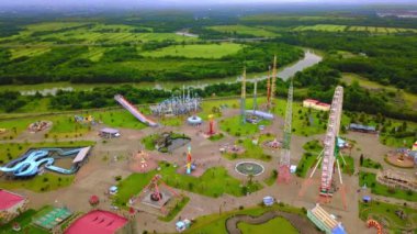 Top view of amusement park with Ferris wheel and roller coaster at sunset in Georgia at Tsitsinatela Park. Ferris wheel with air illumination. Recreation area of Georgian park on Black Sea coast.