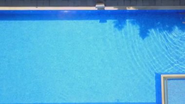 Aerial view from flying drone of people having fun, playing and resting in water in pool. kurt or villa with vacationers. Party of friends or celebration. Sun beds and young people sunbathe in sun.