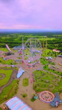 Top view of amusement park with Ferris wheel and roller coaster at sunset in Georgia at Tsitsinatela Park. Ferris wheel with air illumination. Recreation area of Georgian park on Black Sea coast.