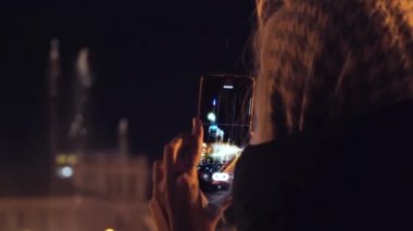 Girl traveler photographs singing fountains on square in Batumi, Georgia. Concept of happy holiday and visiting famous sights. Woman with stolen handkerchief on her head or handkerchief. Cool.