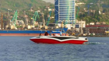 BATUMI, GEORGIA - MAY 22, 2022: Tourist and pleasure boats and yachts ride on sea against backdrop of port and mountains. Touristic place in resort. Rest on water.