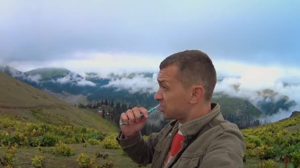 Young Man Brushes His Teeth While Standing Outdoors Hill Mountains — Vídeos de Stock