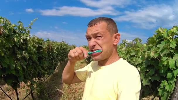 Young Man Brushes His Teeth While Standing Outdoors Backdrop Vineyards — 图库视频影像
