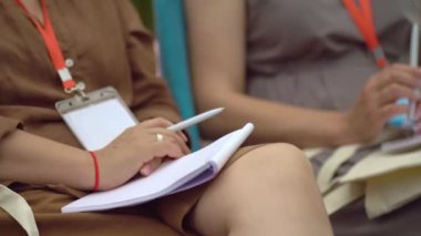 Close-up view of hand of person writing in notebook, holding pen, making notes about scheduling new meetings, information in organizer of personal paper of planner at table. close-up.