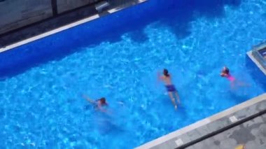 Antenna of friends having fun in pool. Happy young people relax in luxury resort on sunny day. View from above. Girls in bikinis sunbathe in sun.
