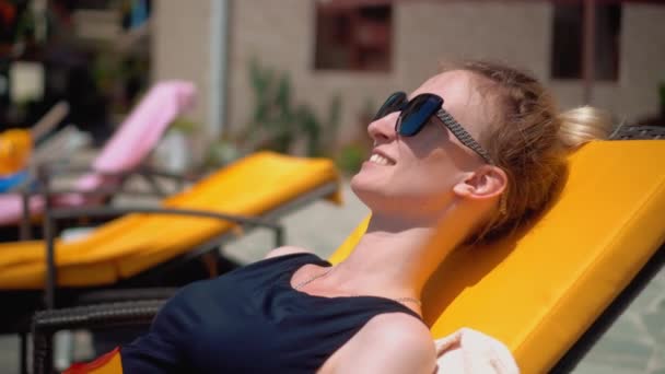 Woman Sun Protective Glasses Black Swimsuit Lies Chaise Longue Pool — Stockvideo