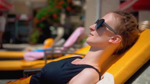 Woman Sun Protective Glasses Black Swimsuit Lies Chaise Longue Pool — Video Stock