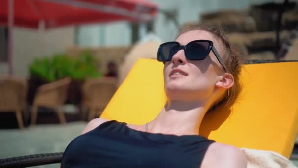 Woman Sun Protective Glasses Black Swimsuit Lies Chaise Longue Pool — Video Stock