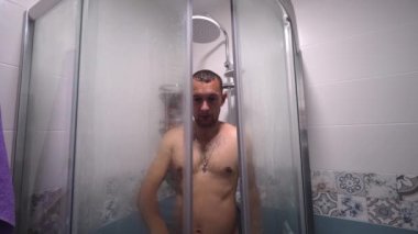 Man taking shower washes his hair underwater in shower in shower. Person's shower in home lifestyle. Morning body care routine for young adults. guy sings and fools around to music.