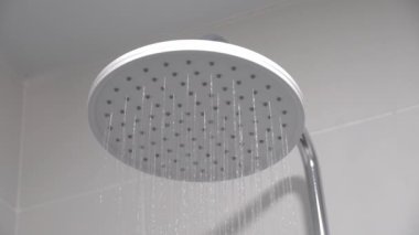 Fresh shower with splashes of water droplets. Water flows from shower head and faucet in modern bathroom. rain shower. Turn on water jet in form of rain.