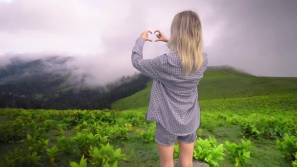 Young Girl Shows Her Heart Her Fingers Background Clouds High — ストック動画