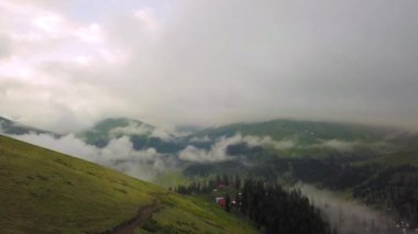 Mountains in clouds spread on ground. View from height of drone above clouds of mountain village of Bakhmaro in Georgia. high-altitude village in clouds at dawn. Beautiful mountain landscape