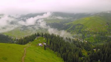 Mountains in clouds spread on ground. View from height of drone above clouds of mountain village of Bakhmaro in Georgia. high-altitude village in clouds at dawn. Beautiful mountain landscape