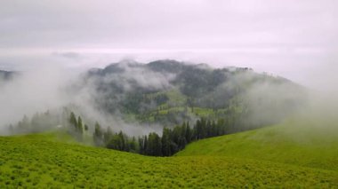 Mountains in clouds spread on ground. View from height of drone above clouds of mountain village of Bakhmaro in Georgia. high-altitude village in clouds at dawn. Beautiful mountain landscape