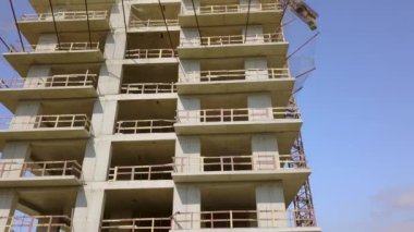 With Close-up of construction site and building. Shooting drone, it flies around only building under construction from side and shows all its floors without windows and walls. Real estate developer.