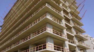 With Close-up of construction site and building. Shooting drone, it flies around only building under construction from side and shows all its floors without windows and walls. Real estate developer.