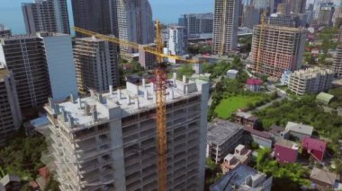 Construction of new multi-storey buildings. Construction crane on construction site against backdrop of mountains sea city. View from drone. New apartments and real estate development. Batumi, Georgia