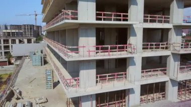 With Close-up of construction site and building. Shooting drone, it flies around only building under construction from side and shows all its floors without windows and walls. Real estate developer.