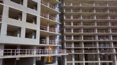 With Close-up of construction site and building. Shooting drone, it flies around only building under construction from side and shows all its floors without windows and walls. Real estate developer.