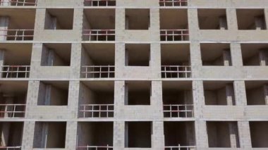 With Close-up of construction site and building. Shooting drone, it flies around only building under construction from side and shows all its floors without windows and walls. Real estate developer.