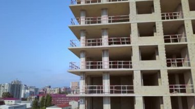 With Close-up of construction site and building. Shooting drone, it flies around only building under construction from side and shows all its floors without windows and walls. Real estate developer.