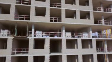 With Close-up of construction site and building. Shooting drone, it flies around only building under construction from side and shows all its floors without windows and walls. Real estate developer.