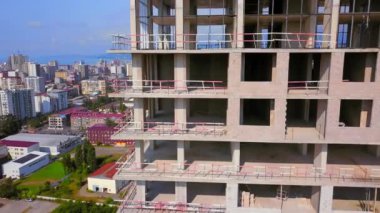 Construction of new multi-storey buildings. Construction crane on construction site against backdrop of mountains sea city. View from drone. New apartments and real estate development. Batumi, Georgia
