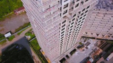 With Close-up of construction site and building. Shooting drone, it flies around only building under construction from side and shows all its floors without windows and walls. Real estate developer.