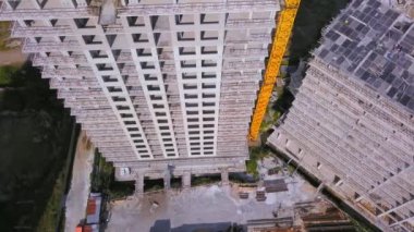 With Close-up of construction site and building. Shooting drone, it flies around only building under construction from side and shows all its floors without windows and walls. Real estate developer.