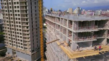 Large construction site of residential building with workers. Modern monolithic construction. Many different workers on construction site. Construction of reinforced concrete structures. View from drone.