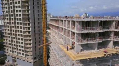 Large construction site of residential building with workers. Modern monolithic construction. Many different workers on construction site. Construction of reinforced concrete structures. View from drone.