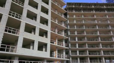 With Close-up of construction site and building. Shooting drone, it flies around only building under construction from side and shows all its floors without windows and walls. Real estate developer.