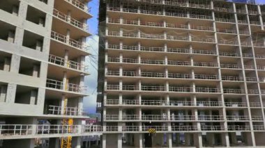 With Close-up of construction site and building. Shooting drone, it flies around only building under construction from side and shows all its floors without windows and walls. Real estate developer.