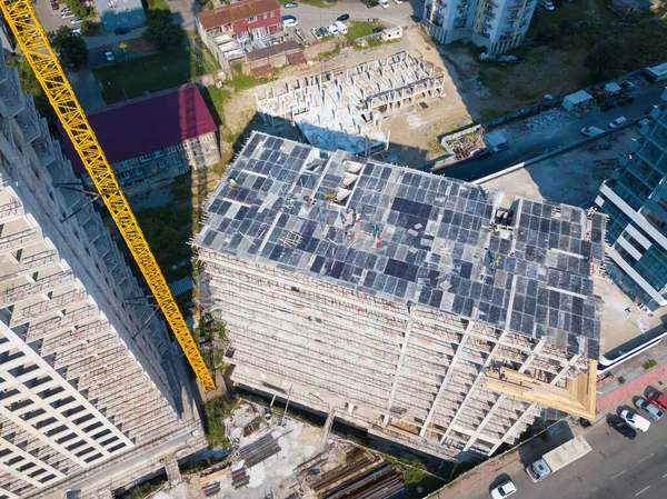 Drone view of the construction of a multi-storey building, a construction crane on a sunny day