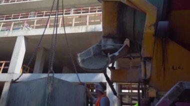 Batumi, Georgia - 2 may 2022: Mixer truck is transport cement to casting place on building site, Selective focus. Concrete is poured into container for transportation by crane to upper floors.