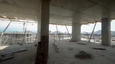 Camera moves around construction site of high building with view of city on sunny day. Apartment building under construction. Developer, real estate investment. concrete monolithic piles.