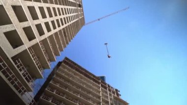 Turna ve çok katlı yeni binalar. Sanayi temelli. Mavi gökyüzüne karşı inşaat alanında çalışmak. Yüksek binaların dipteki manzarası. Müteahhit ya da müteahhit işi.