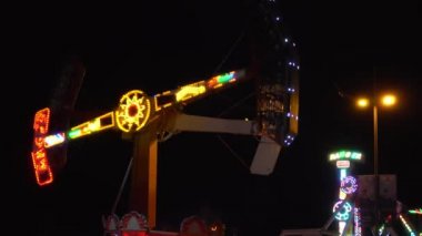 Dönen vagon şeklinde gece çekimi, insanlar çığlık atıyor ve eksen etrafında dönüyorlar. Özel bir yer, adil ya da festival. Saray şehri, korkunç açık hava atlıkarıncaları..