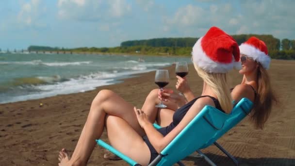 Szczęśliwe Dziewczyny Bikini Siedzą Krzesłach Świętując Boże Narodzenie Plaży Pijąc — Wideo stockowe