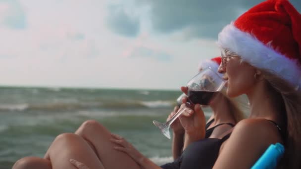 Gelukkige Meisjes Bikini Zitten Stoelen Kerstmis Vieren Het Strand Wijn — Stockvideo