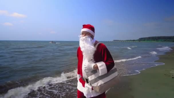 Kerstman Pak Loopt Langs Kust Met Een Tas Zijn Schouder — Stockvideo