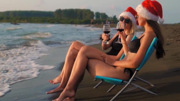 Happy Girls Bikinis Sit Chairs Celebrating Christmas Beach Drinking Wine — Stock video