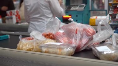 BATUMI, GEORGIA - MAYIS 07, 2022: Süpermarketteki kasada çeşitli ürünler. Süpermarketteki kasiyer kız kafa bandına ürünler seriyor. Kadın kasiyer dükkanın kasasında mal satıyor.