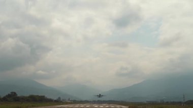 Büyük modern yolcu uçağı, bulutların ve dağların arka planına karşı açık güneşli bir havada havaalanından havalanır. Modern yolcu hava taşımacılığı.